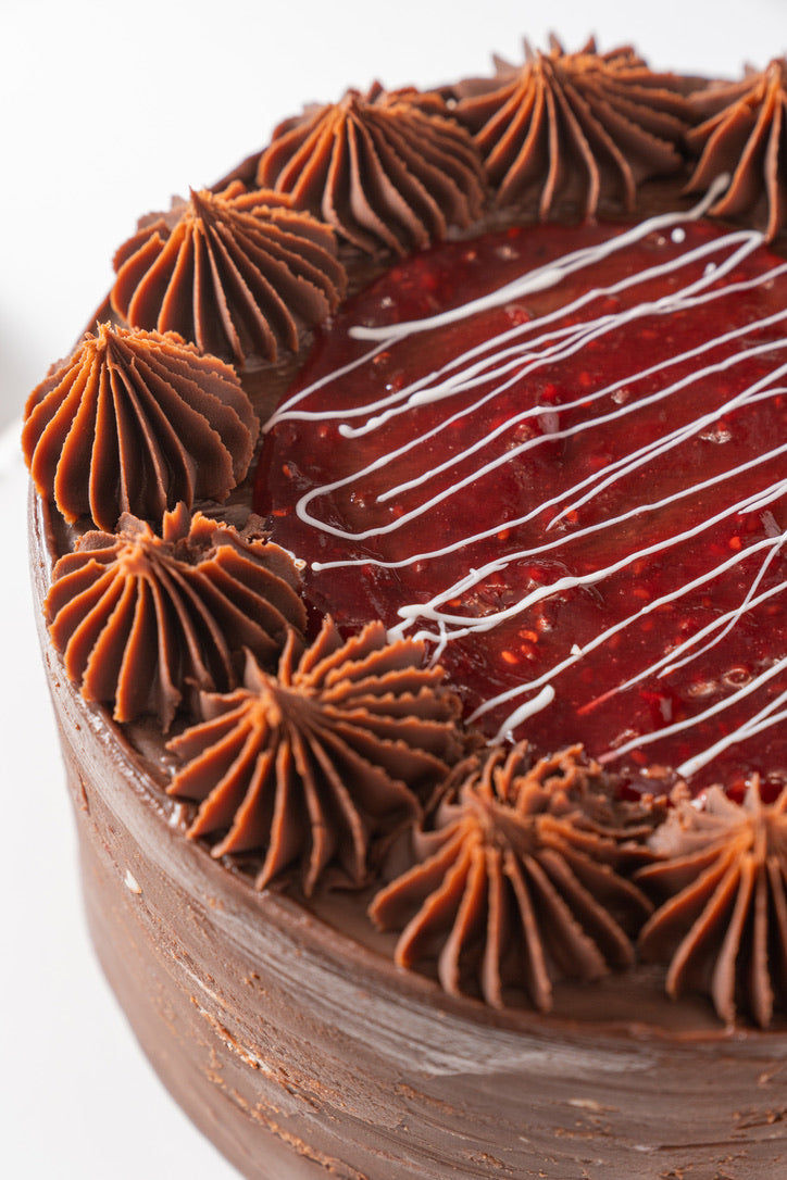 Torta de frambuesa, chocolate y trufa, con láminas de chocolate blanco.